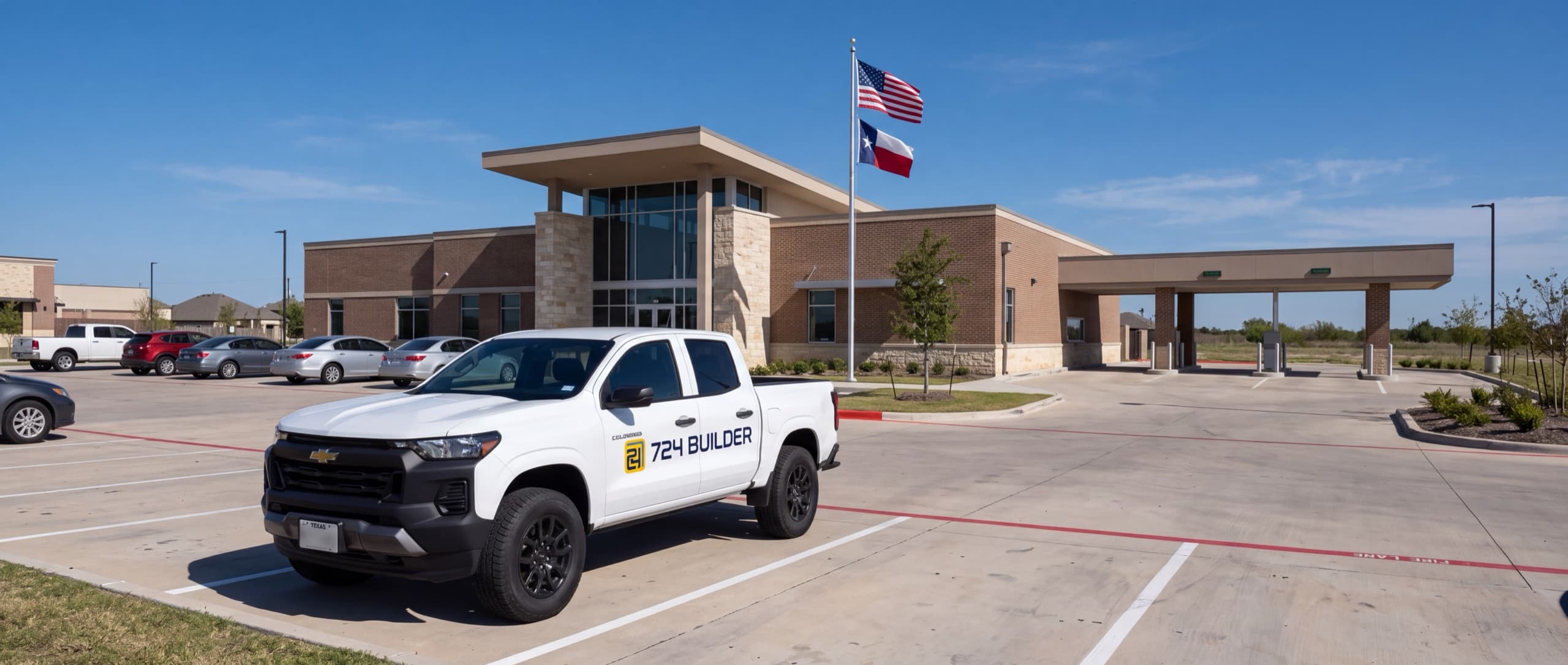 A 724 Builder pickup parked in the lot outside a community bank branch, with the United States and Texas flags flying by the entrance.